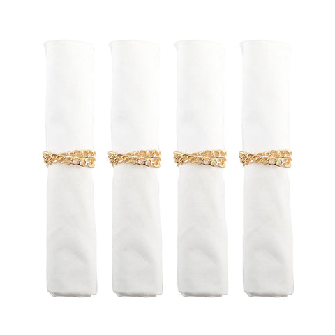 Set di 4 portatovaglioli in metallo dorato a forma di catena disposti con eleganza su tovaglioli in tessuto bianco