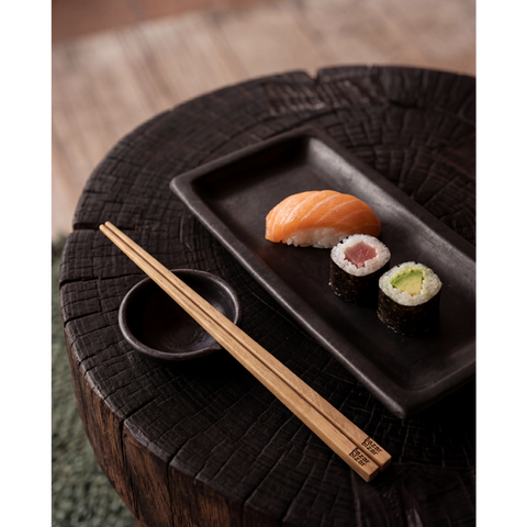 Piatto rettangolare in terracotta nera color carbone The Burned 25x12 cm con una composizione elegante di sushi colorato su un tavolo in legno naturale