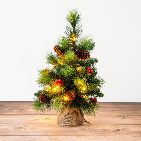 Mini albero di Natale a LED con bacche rosse e pigne alto 45 cm posizionato su una consolle in legno chiaro in un ingresso accogliente in stile Japandi