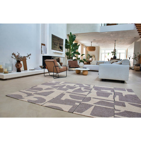 Tappeto flatweave ecologico con geometrico motivo decostruttivista nei toni del grigio e del marrone Papercut String di Louis De Poortere steso in un soggiorno moderno