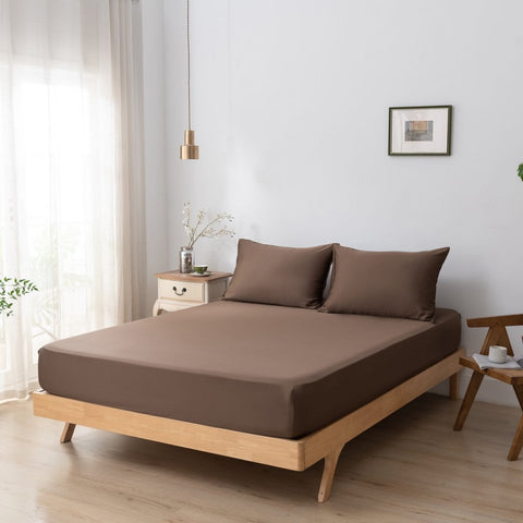 Lenzuolo con angoli in seta di bambù marrone caffè teso con cura su un letto matrimoniale in un ambiente moderno e luminoso