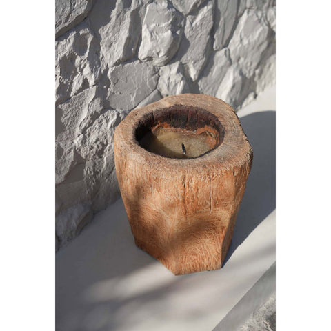 Candela scultorea in tronco di legno accesa posizionata a terra