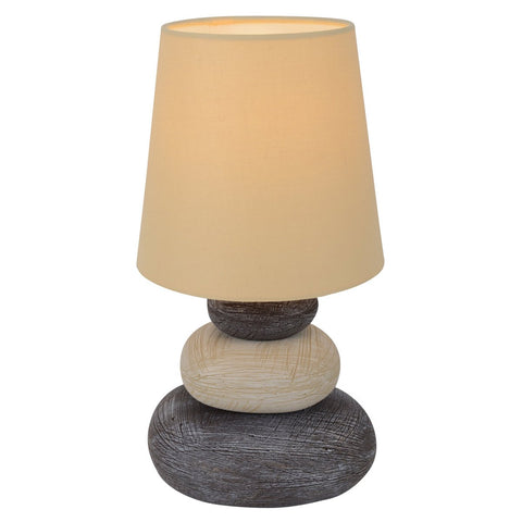 Lampada da tavolo in ceramica ad effetto pietra naturale con paralume in tessuto chiaro Stoney alta 31 cm posizionata su un comodino in legno in un ambiente notte stile Japandi