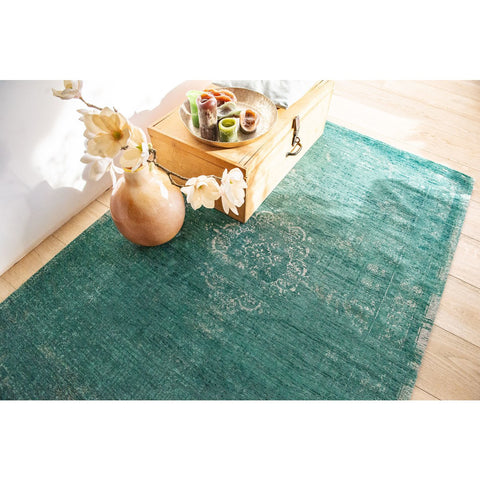 Tappeto flatweave in ciniglia e lana verde giada con medaglione centrale e finitura vintage sbiadita Medallion di Louis De Poortere steso su un pavimento in parquet chiaro in un soggiorno Japandi