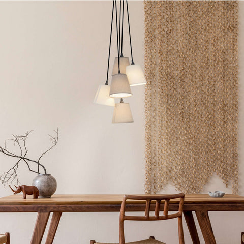 Lampada a sospensione con 5 paralumi sfalsati in tessuto di cotone beige e marrone Boho alta 95 cm sospesa sopra un tavolo da pranzo in legno di rovere chiaro in un soggiorno Japandi