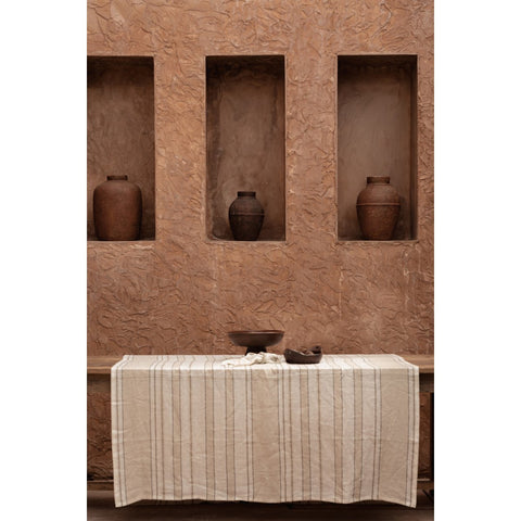 Tovaglia a righe in lino La Provenza allestita su un grande tavolo da pranzo con ceramiche neutre e posate scure.
