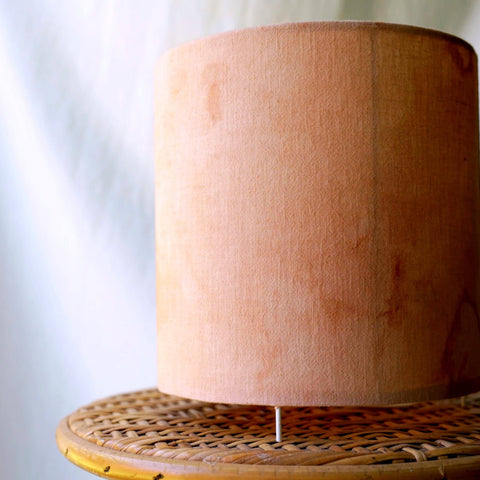 Lampada da tavolo rosa stile Japandi che diffonde una luce soffusa e intima sul comodino di una camera da letto