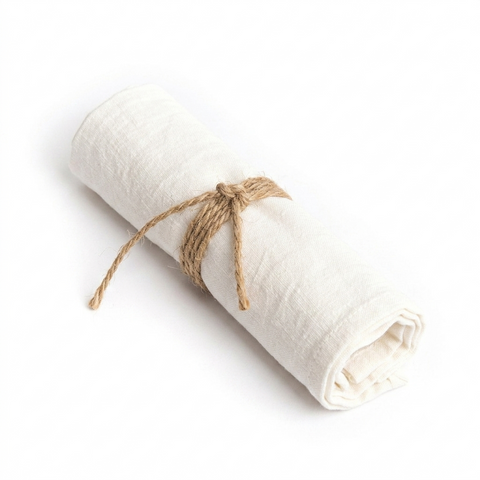 Tovagliolo in puro lino bianco naturale piegato delicatamente su un tavolo da pranzo in legno