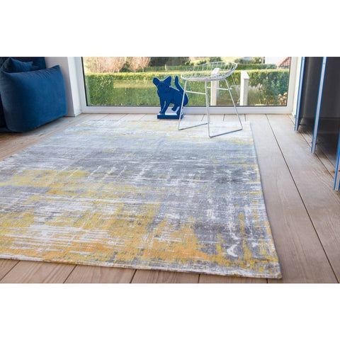 Tappeto rotondo astratto giallo solare e bianco Sea Bright Sunny di Louis De Poortere posizionato al centro di un soggiorno luminoso con parquet in legno chiaro