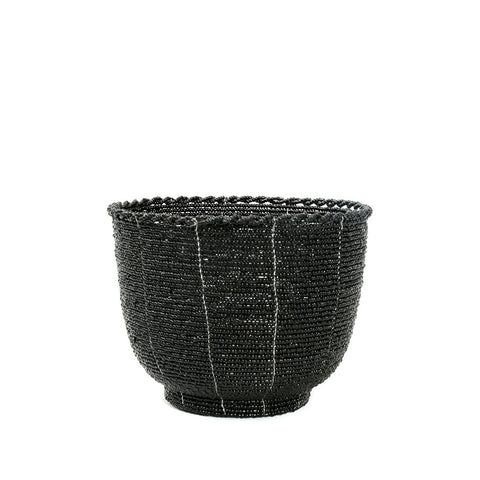 Ciotola decorativa intrecciata a mano con piccole perline nere fatta in Indonesia posizionata su un tavolino da caffè con piccoli oggetti all'interno